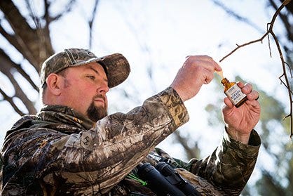 Man Holding Code Blue Deer Scent in Woods 